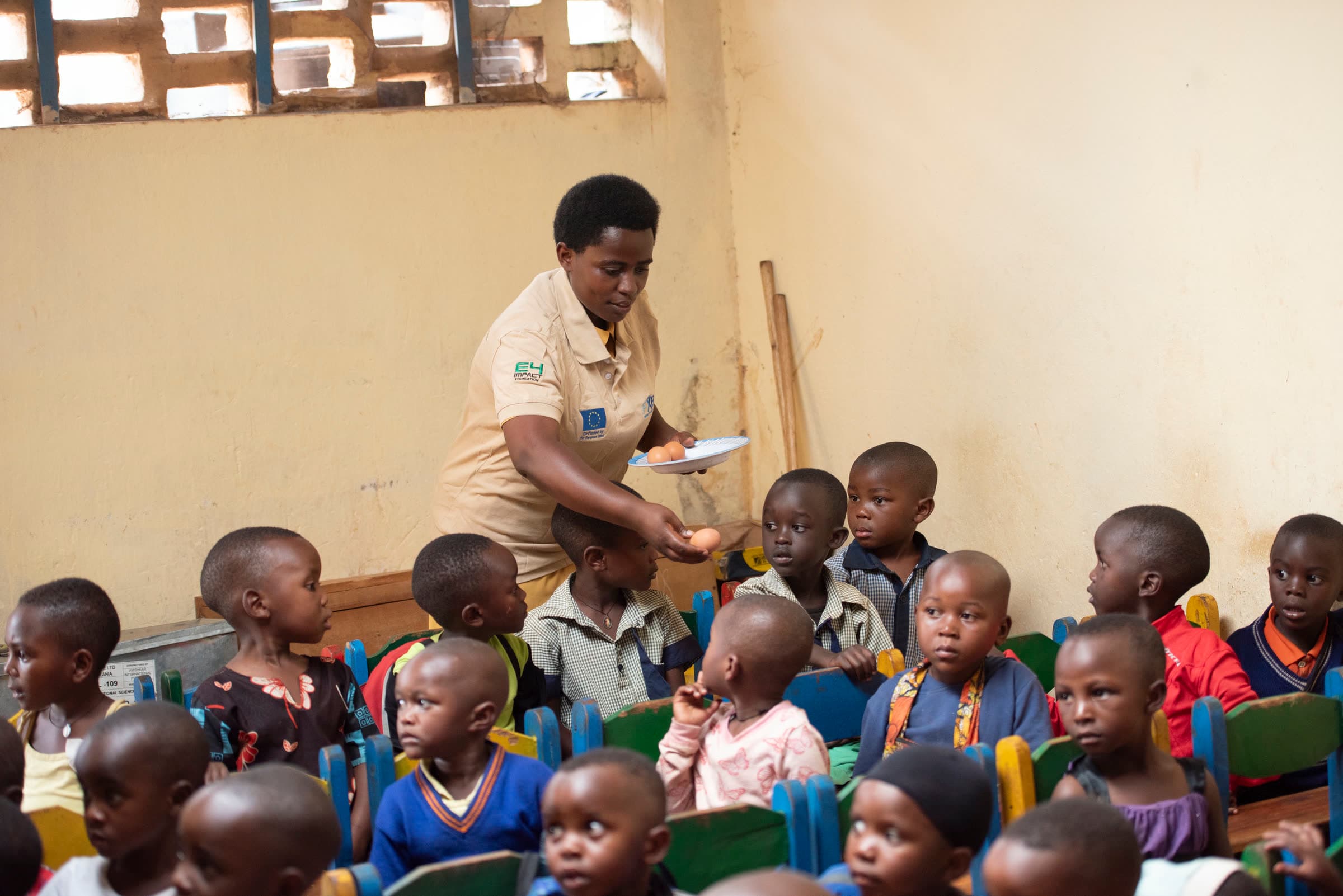 A community health worker leading a session with young children seated in a classroom