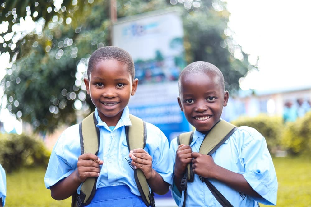 Two children in school uniform carrying their bags